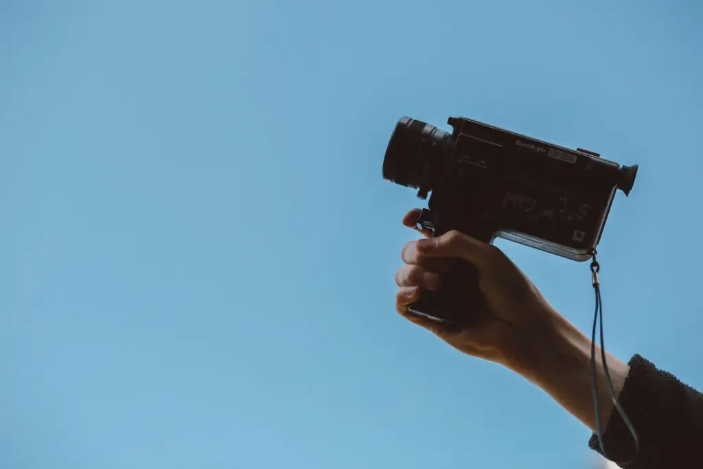 An image of someone holding a camera representing Soulheart's blog titled Crack The Code How To Succeed On YouTube [Strategy Guide].
