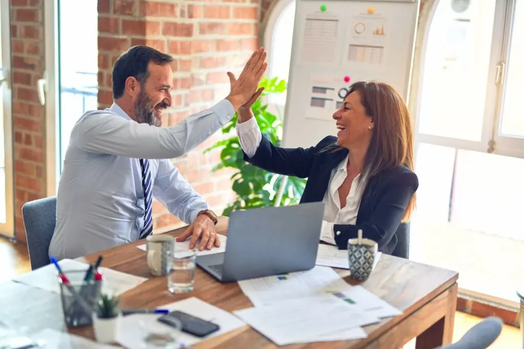 Image of a business man and business woman high fiving representing Soulheart's blog titled How Can a NonProfit Organization Apply for Google Ads?