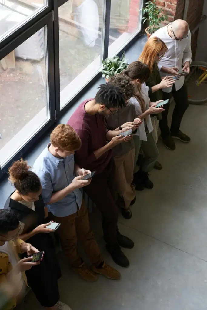 An image of a row of people staring at their phones representing Soulheart's blog Advance Your Career - Social Media Training For Digital Marketers