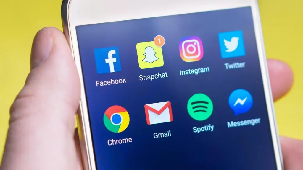 An image of a phone with different social media icons on it representing the need to promote your videos across multiple channels when creating a good YouTube video.