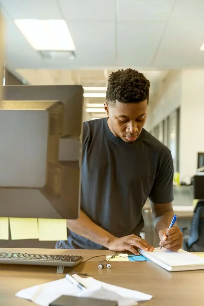 A man writing notes in a notebook in front of a computer representing Soulheart's blog on digital marketing training and digital marketing education.