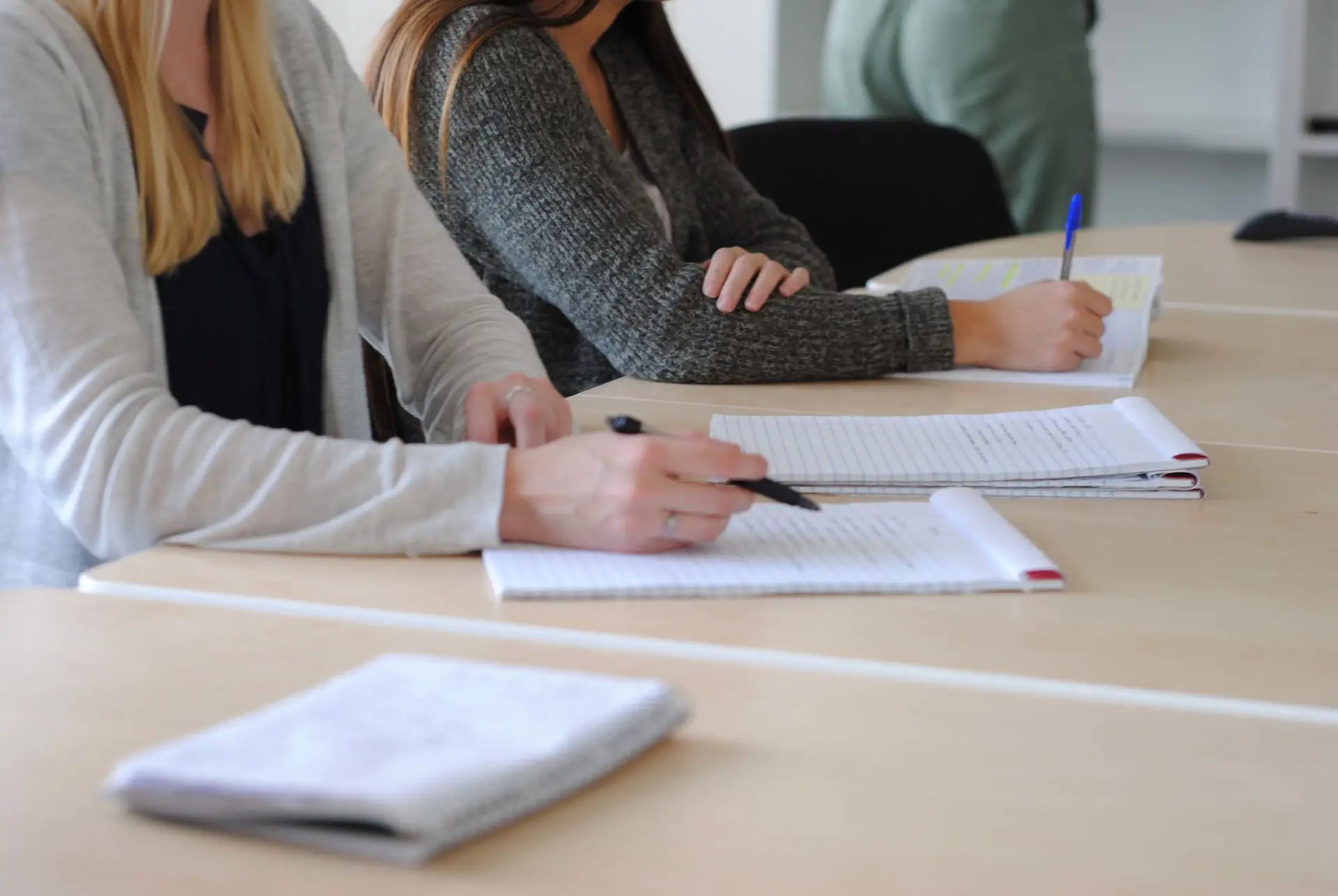 Two women collaborate over a digital marketing strategy on notepads.