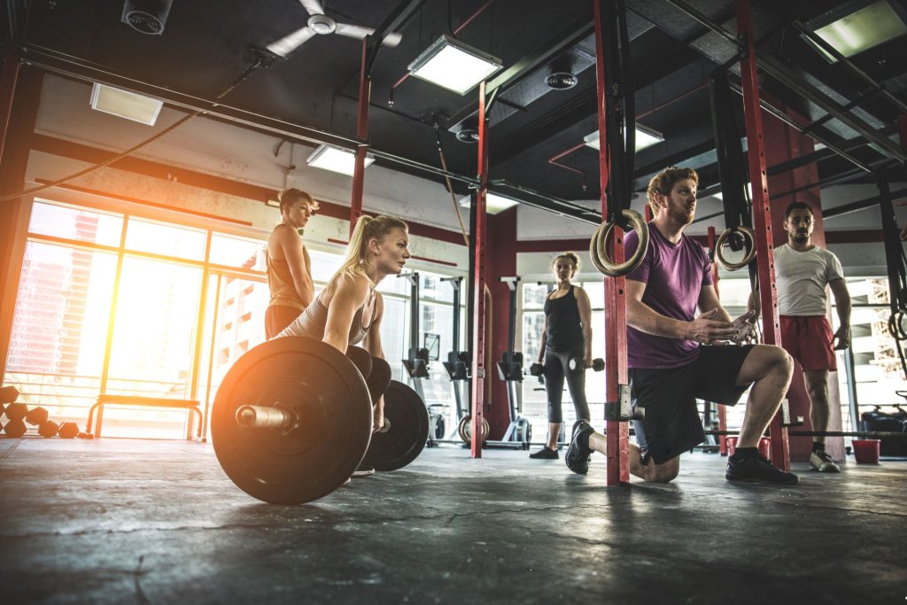 Image of 5 people doing different workouts at a CrossFit gym representing websites for CrossFit gyms.