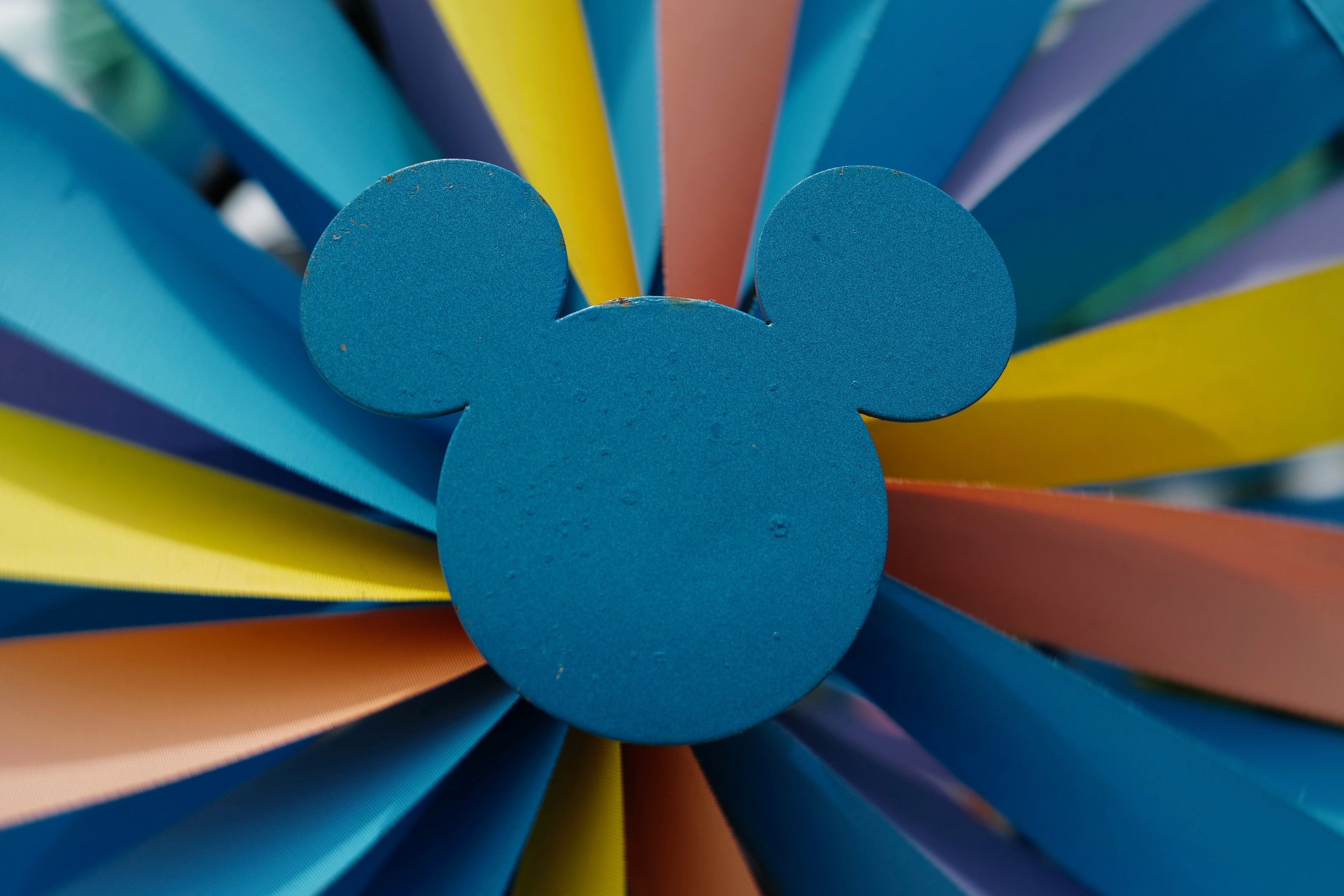 Mickey mouse in front of colorful fan blades.