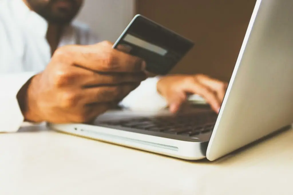 Image of a man on his laptop holding a credit card representing Soulheart's blog titled How Can a NonProfit Organization Apply for Google Ad Grants?