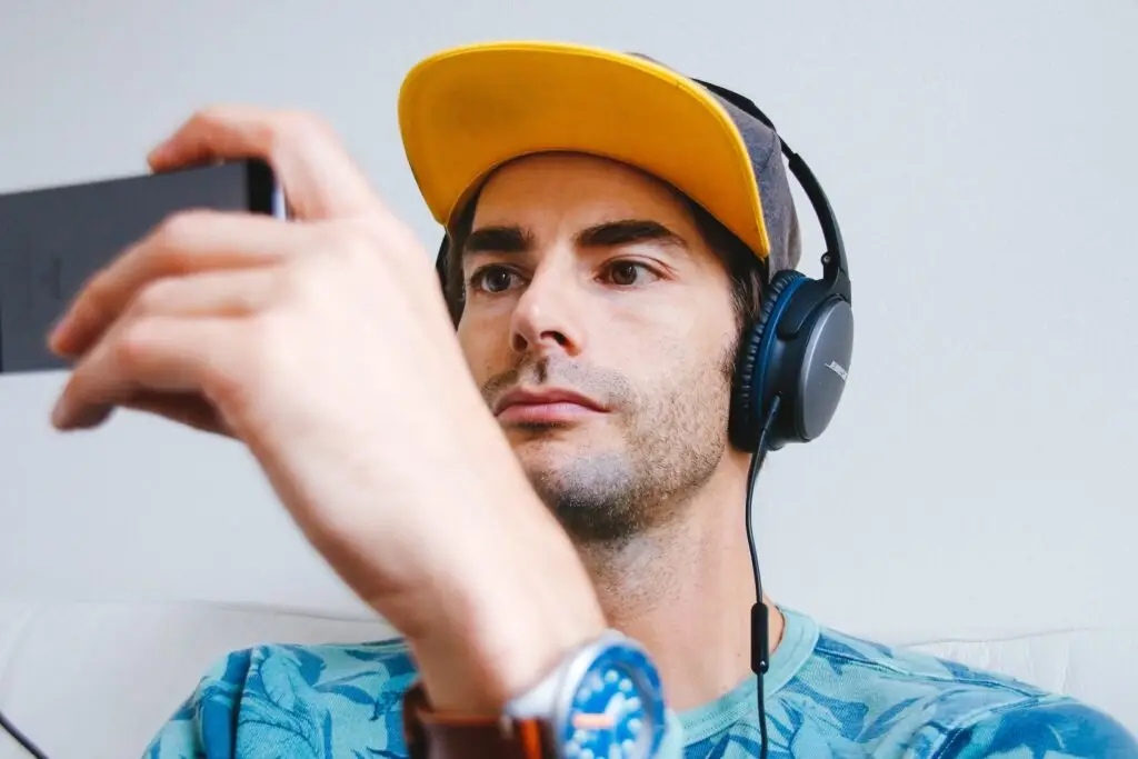 An image of a man watching a video on his phone, representing Soulheart's blog titled Crack The Code How To Succeed On YouTube [Strategy Guide].