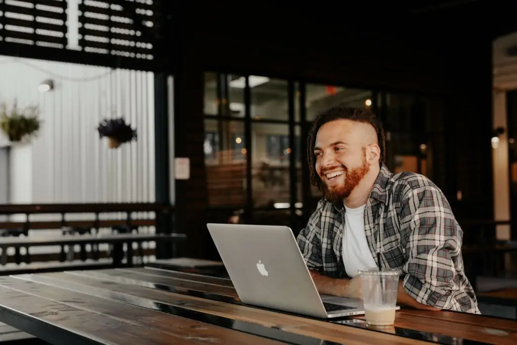 Image of man smiling with his computer in front of him representing Soulheart's blog titled Google Ads for Nonprofit Organizations