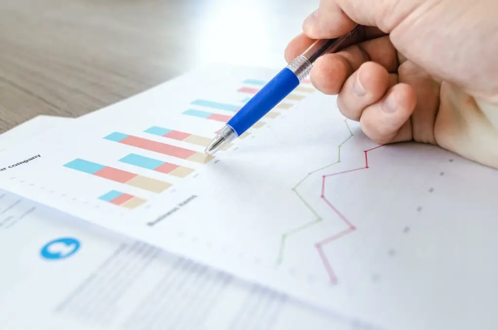 Image of a hand with a pen hovering over papers of graphs and charts representing Soulheart's blog titled Optimizing Your Blog for Search Engines.